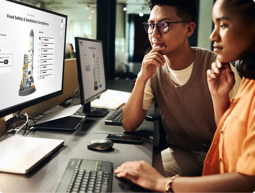 A man and woman looking thoughtfully at a screen with their chin rested on their hand in a thinking pose.